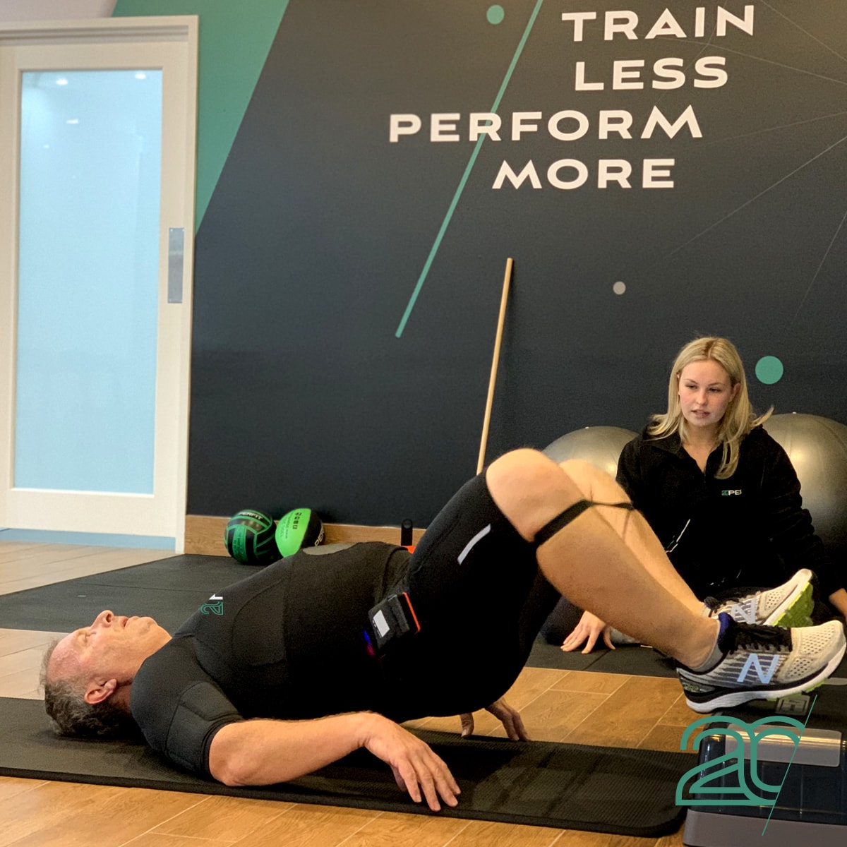 Man Doing Core Exercises with a Personal Trainer Using 20PerFit's EMS Technology