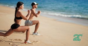 a woman and a man working out at a sand beach 
